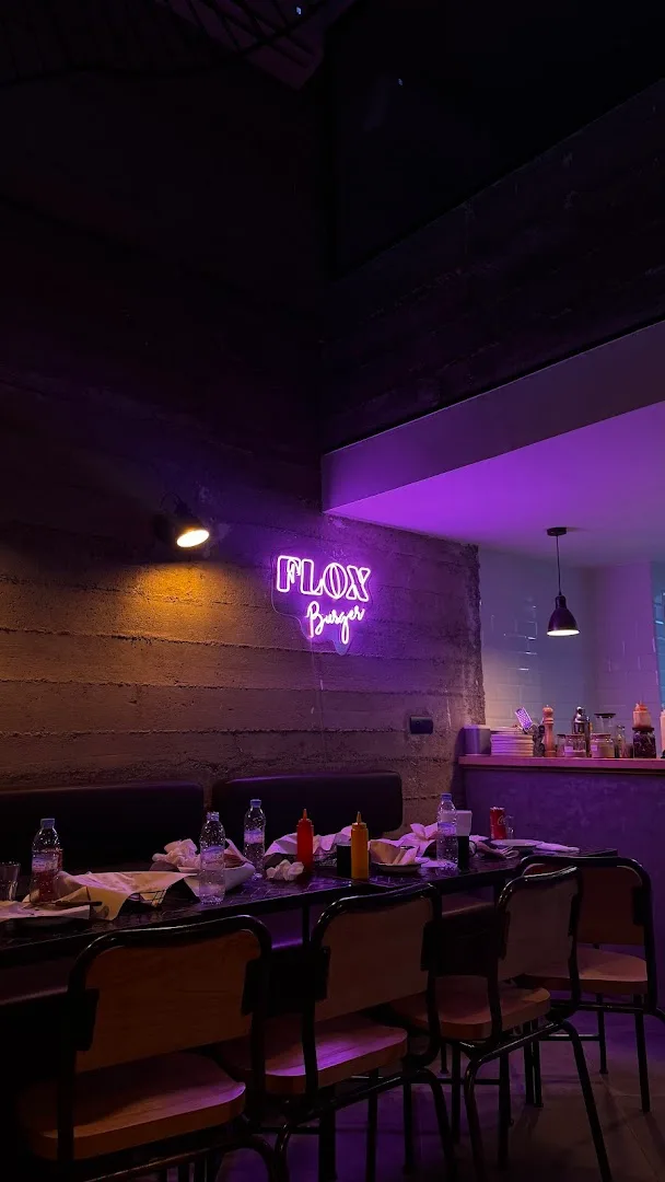 Purple-lit dining room with neon FLOX sign and bar seating
