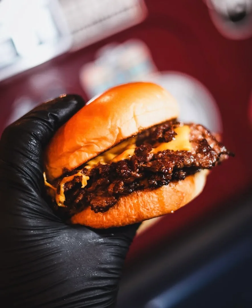 Cheeseburger held in hand with black glove
