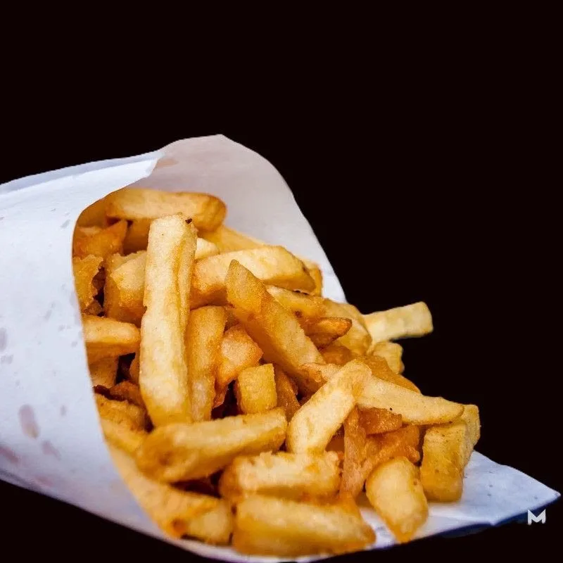 Golden french fries in white paper cone
