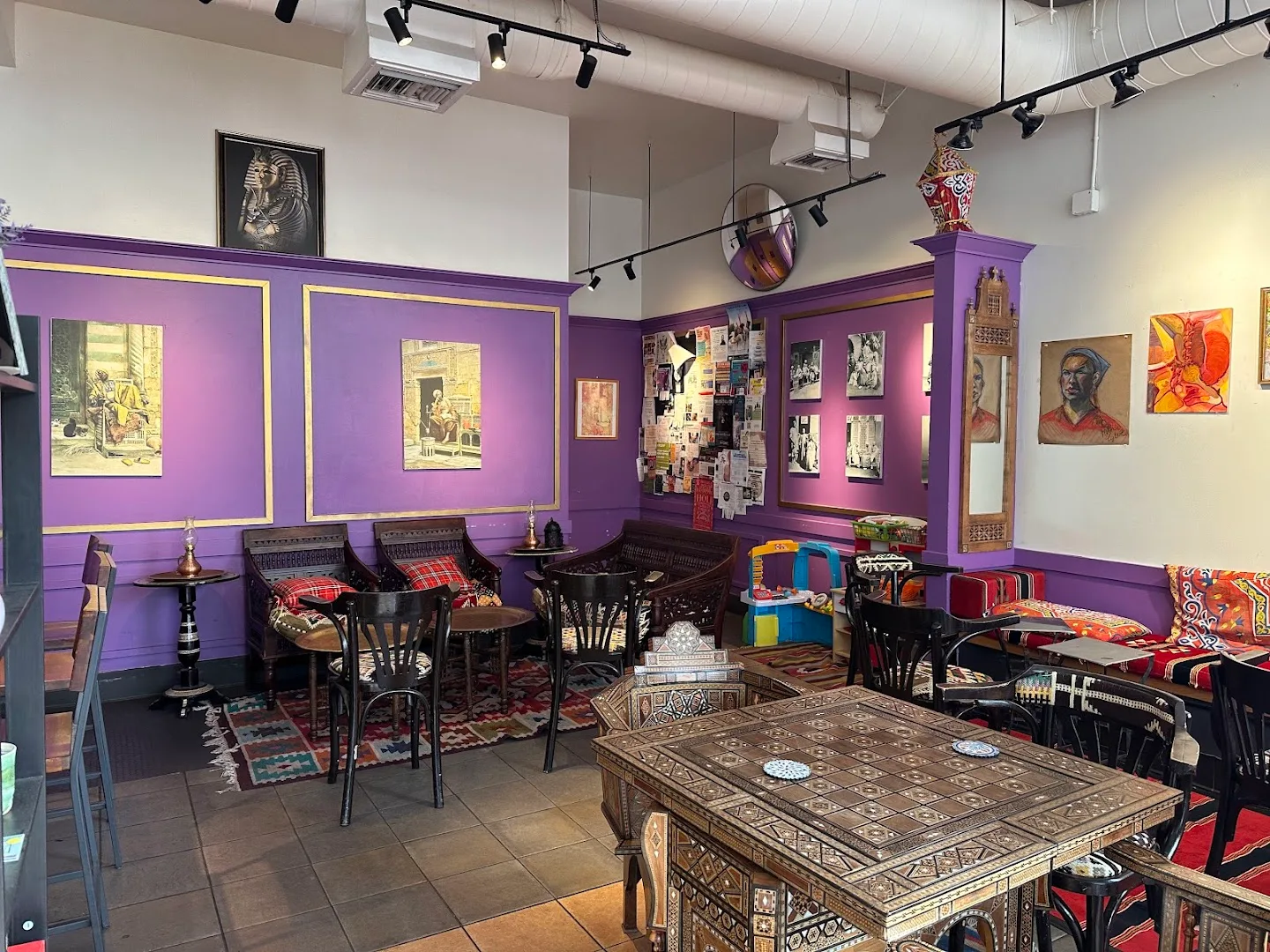 Purple-walled dining room with artwork, black chairs, patterned floor